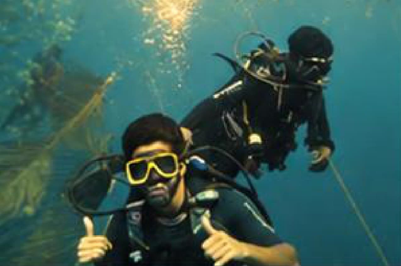 Two scuba divers giving a thumbs-up underwater off the Pondicherry coast.