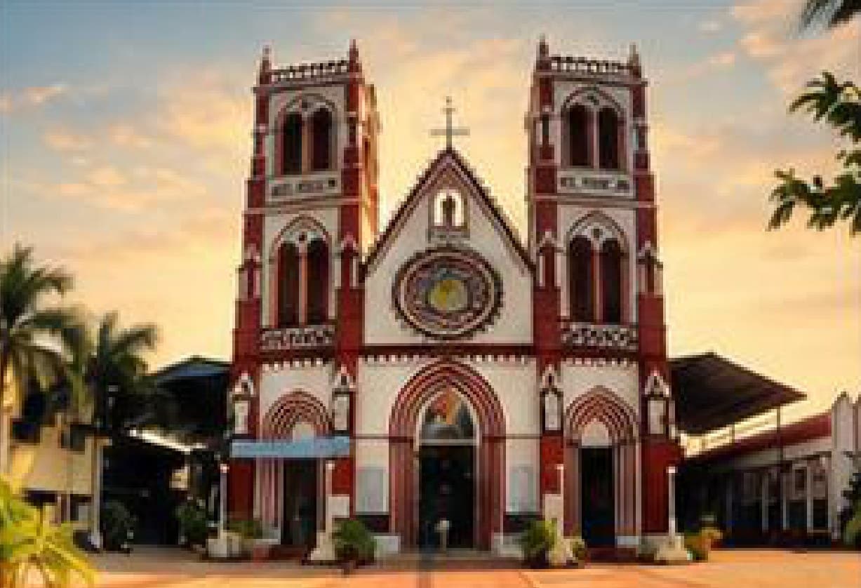 The twin red-and-white Gothic towers of Sacred Heart Basilica in Pondicherry at sunset.