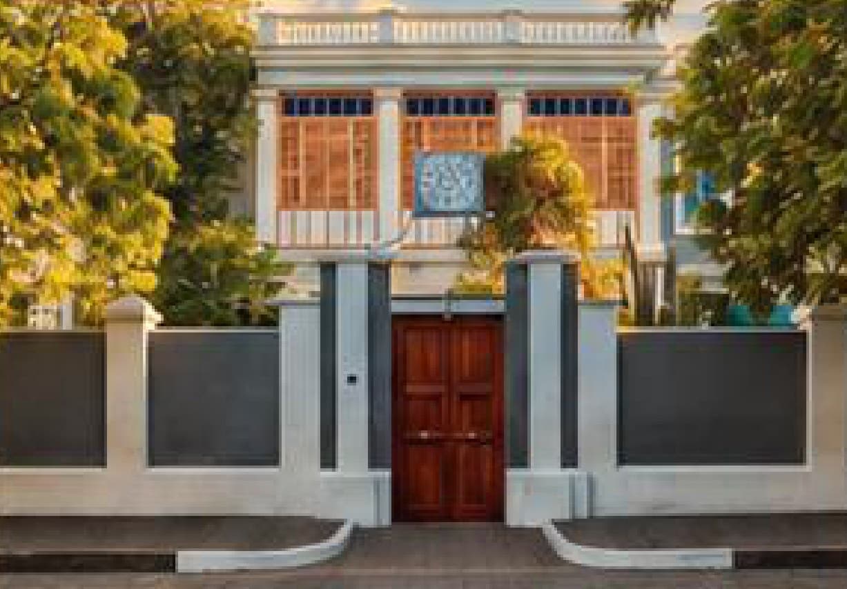The entrance to Sri Aurobindo Ashram in Pondicherry, framed by white walls and a wooden door.