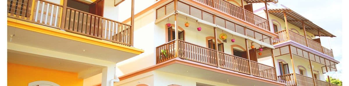 Auroma Phase I — a three-storey building with warm yellow and white balconies and hanging planters.