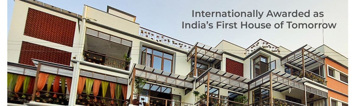 Gratitude Ecovilla, Auroma Phase III — a terraced building with timber pergolas and coloured drapes.